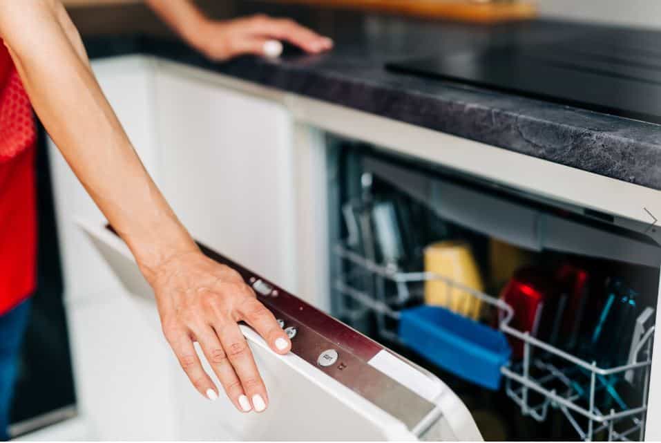 dishwasher being opened by lady wearing a red shirt with white nail polish