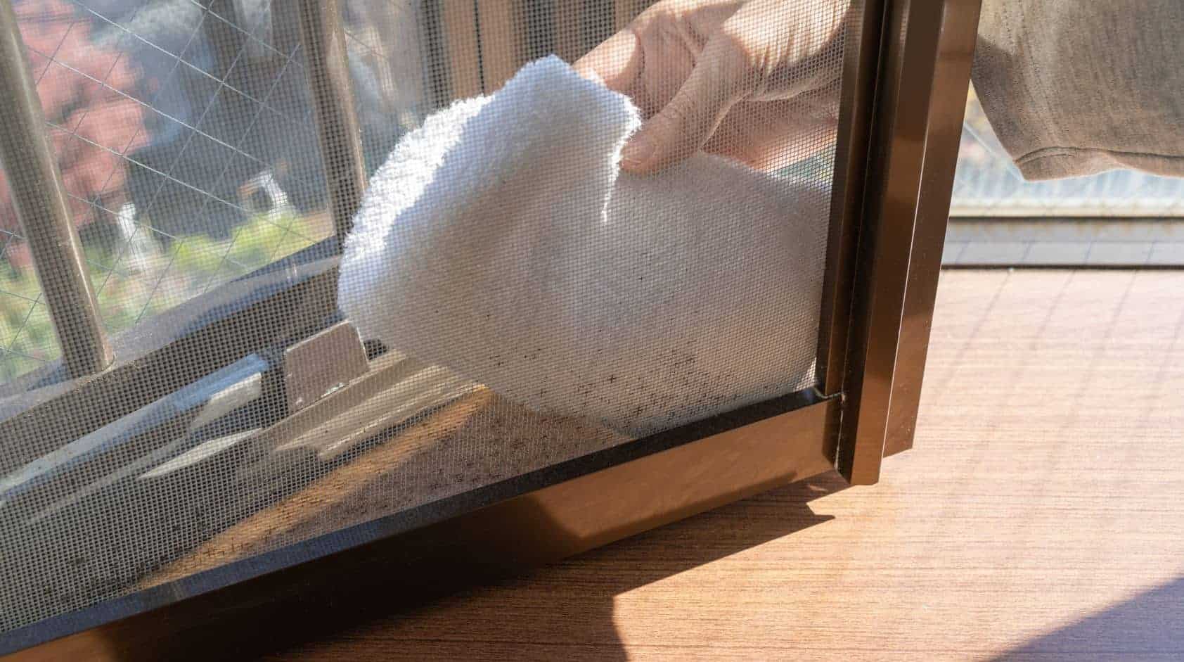 Person wiping down dirty fly screens with white microfibre cloths
