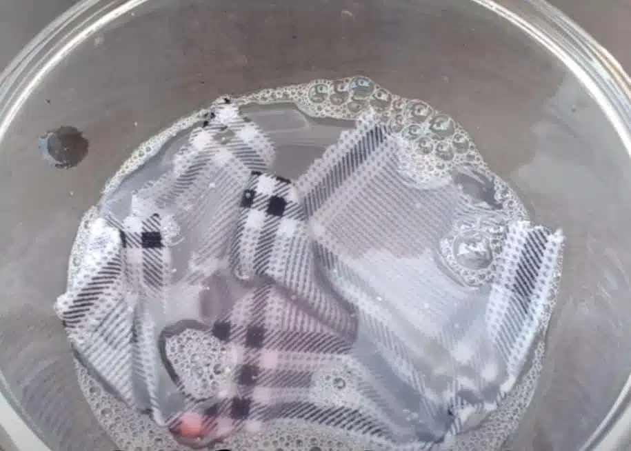 blood soaked scarf being cleaned in a clear large bowl