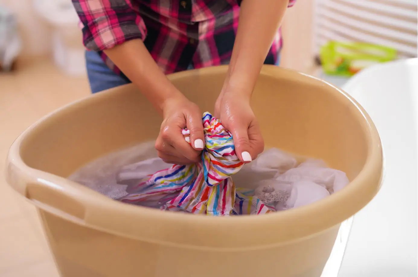 lady handwashing clothes in a fawn coloured tub
