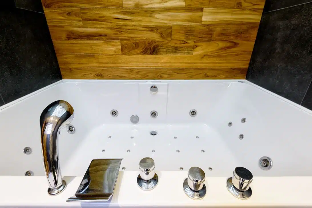 large white and clean jetted tub next to a wooden splash back
