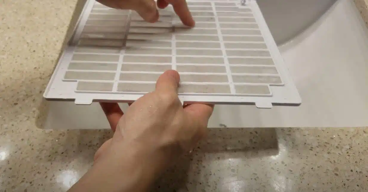 man cleaning air filter of frigidair dehumidifier in a basin