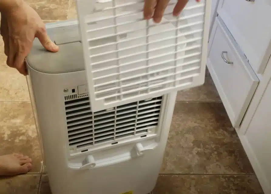 man cleaning the inside of a frigidair dehumidifier