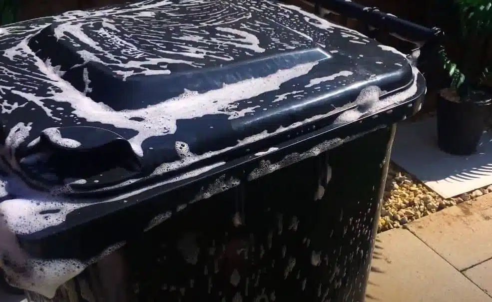 outside of black wheelie bin being cleaned with soapy water