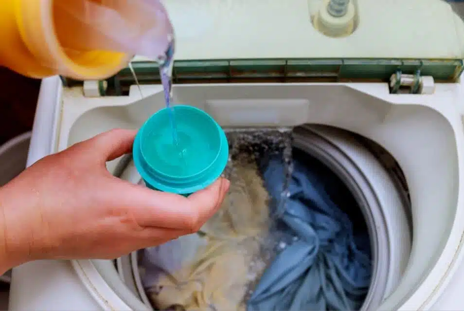 Person pouring washing detergent into top load washer