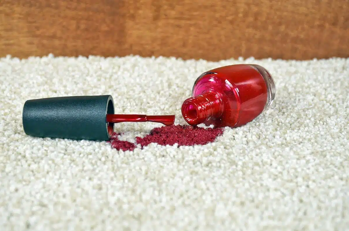red nail polish spilt on a white plush carpet