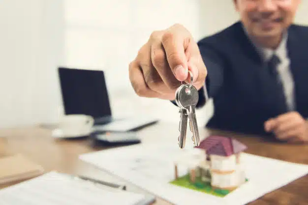 smiling-businessman-as-real-estate-broker-agent-givng-house-keys