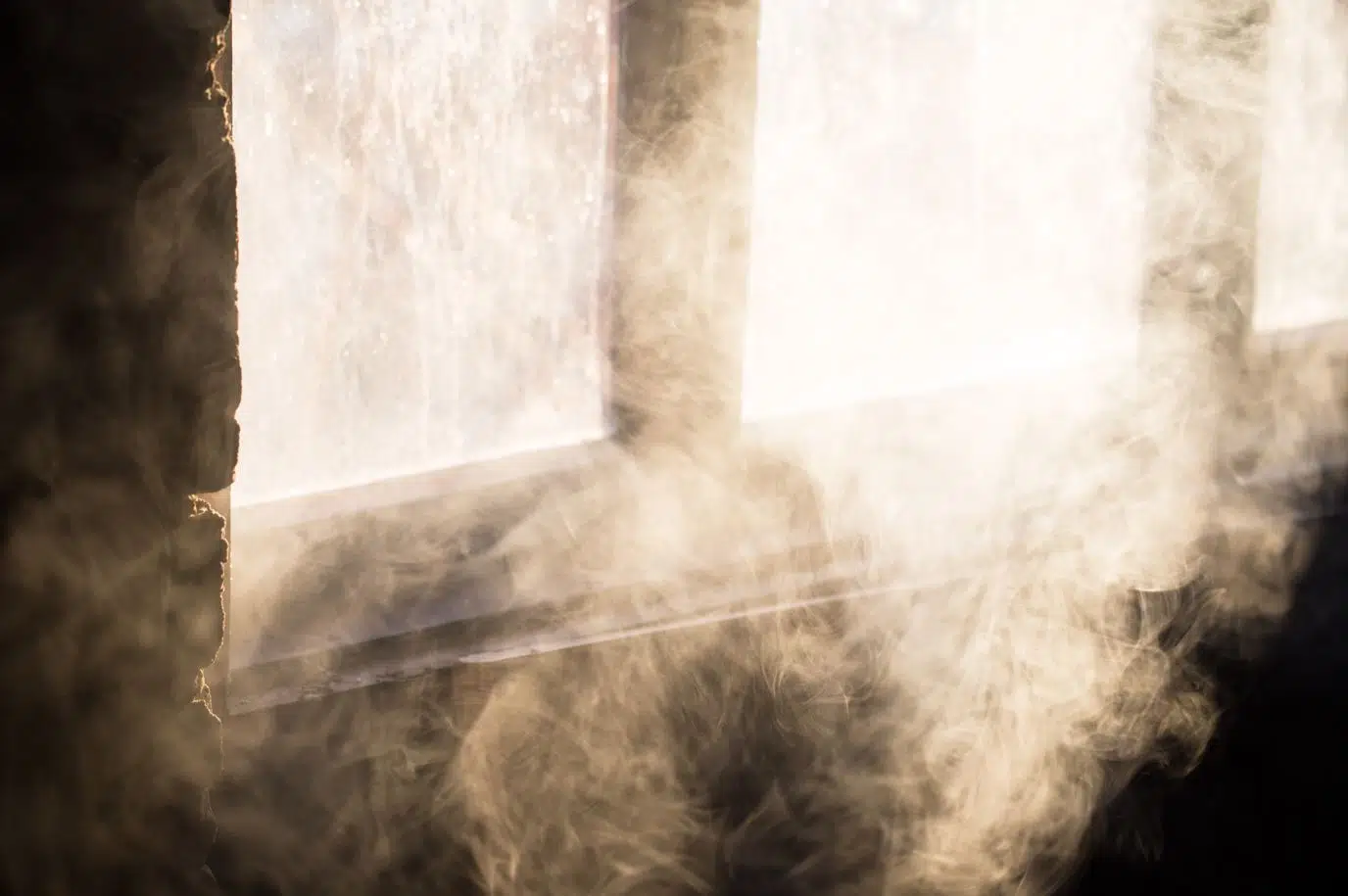 visible smoke inside a house next to a large window