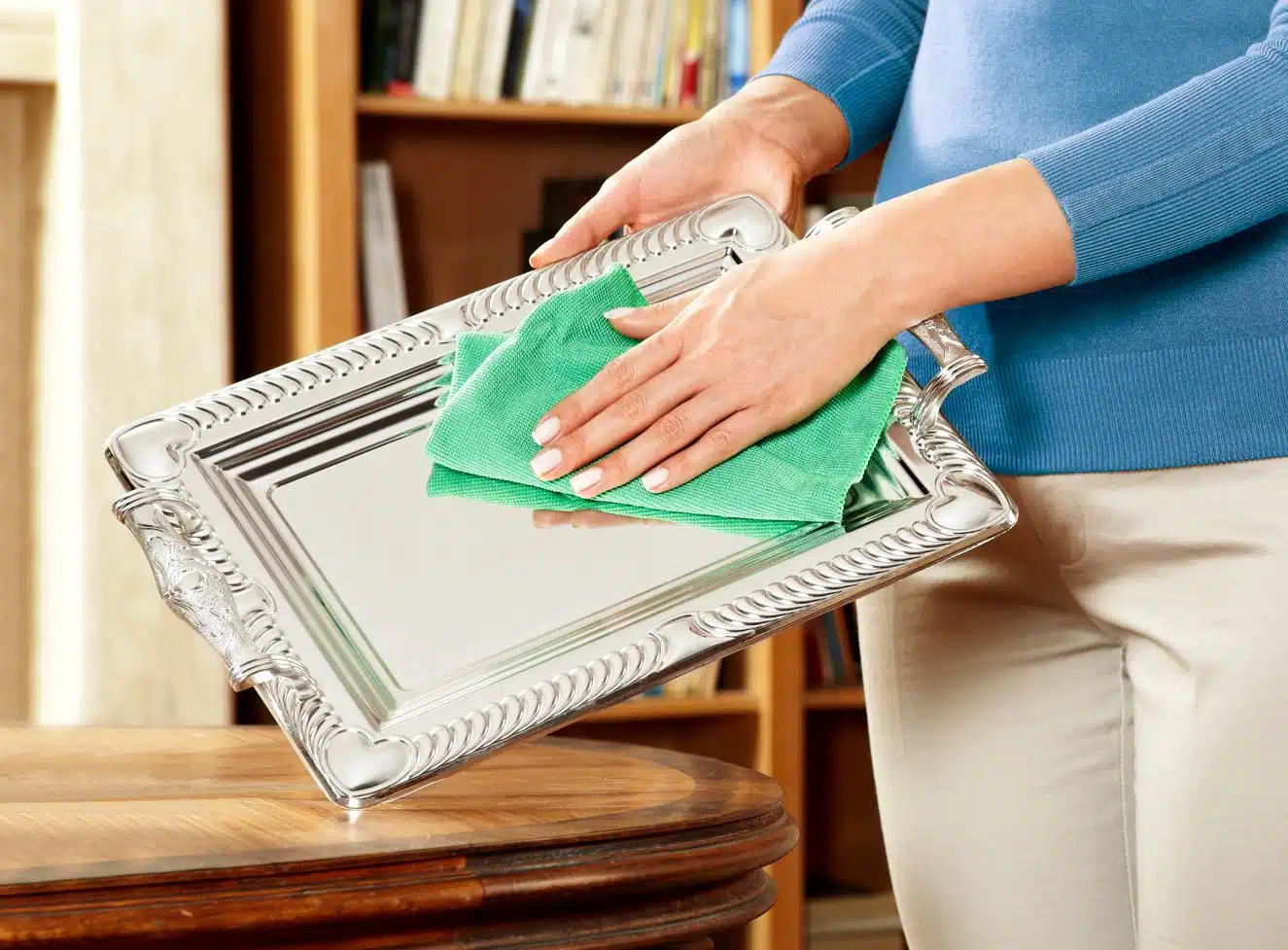 woman using green microfibre cloth to polish pewter plate