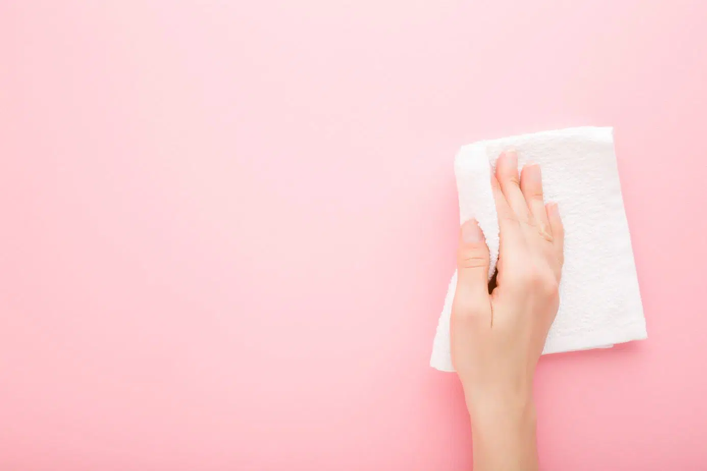 woman wiping down pink wall with a wet white cloth