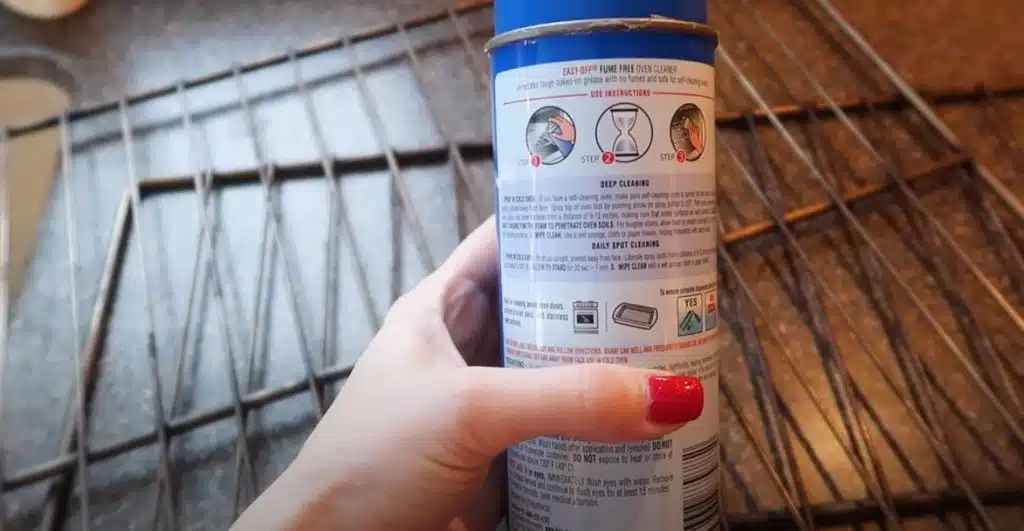 woman with red nail polish reading oven cleaner instructions